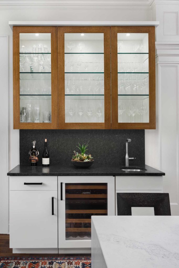 Glass storage in black and white kitchen with wood accents