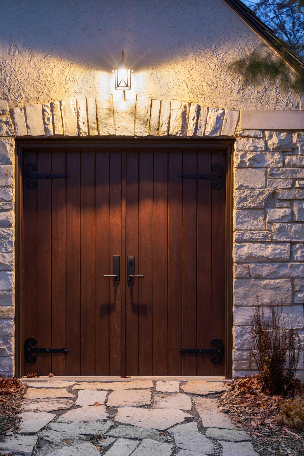 Double wooden entry doors with stone walkway